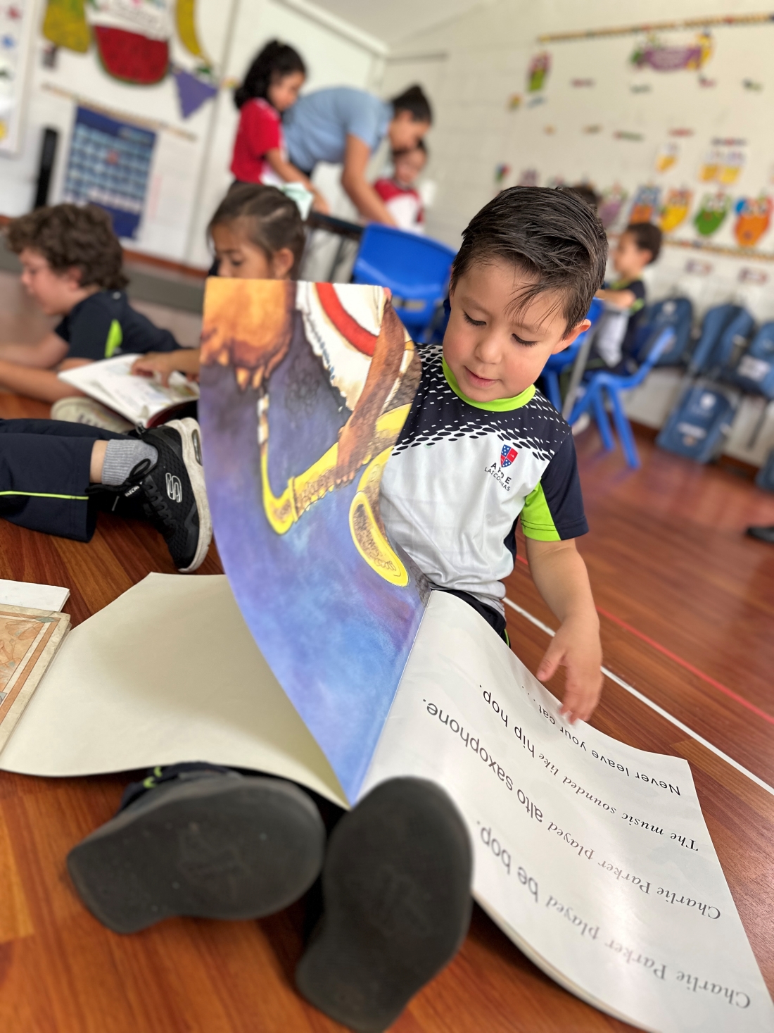 Niño leyendo un libro en inglés en su clase de preprimaria bilingüe APDE Las Colinas